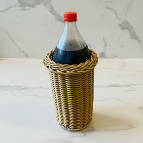 Suporte porta-garrafa pet, de vime sintético, com garrafa de refrigerante de 1,5 litros, na bancada de mármore.