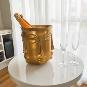 Transforme sua celebração com a champanheira Faces. Design escultural em dourado que une arte e funcionalidade. 