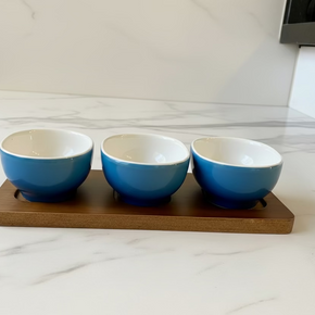 Petisqueira com 3 bowls ovais em cerâmica azul e base de madeira. Design orgânico e moderno para servir com estilo. 