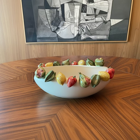 Centro de mesa em cerâmica off white com bordas decoradas com frutas coloridas esculpidas em cerâmica .