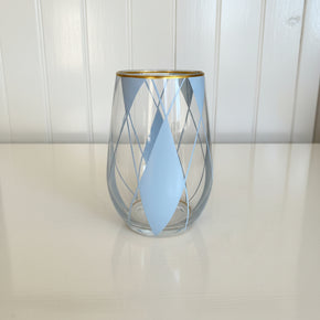Close frontal do sofisticado copo de vidro transparente, Escócia, decorado com um padrão geométrico de losangos  em tons de azul claro, pintado à mão. Detalhe elegante de borda dourada. Peça exclusiva Artes Salles para So Sweet Kasa.
