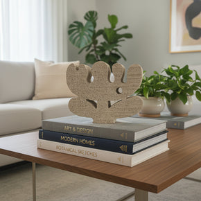 Escultura decorativa Garden Flor horizontal em concreto celular bege areia sobre livros em mesa de madeira. Design orgânico assinado pelo Estúdio OIO. Na So Sweet Kasa.