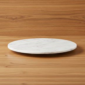 Prato giratório redondo de mármore branco, também usado como bandeja giratória de centro de mesa mostrando o design sutilmente elevado da base sobre fundo amadeirado.