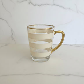 Caneca bege com alça e borda dourada, pintada à mão livre pelo Ateliê Artes Salles.